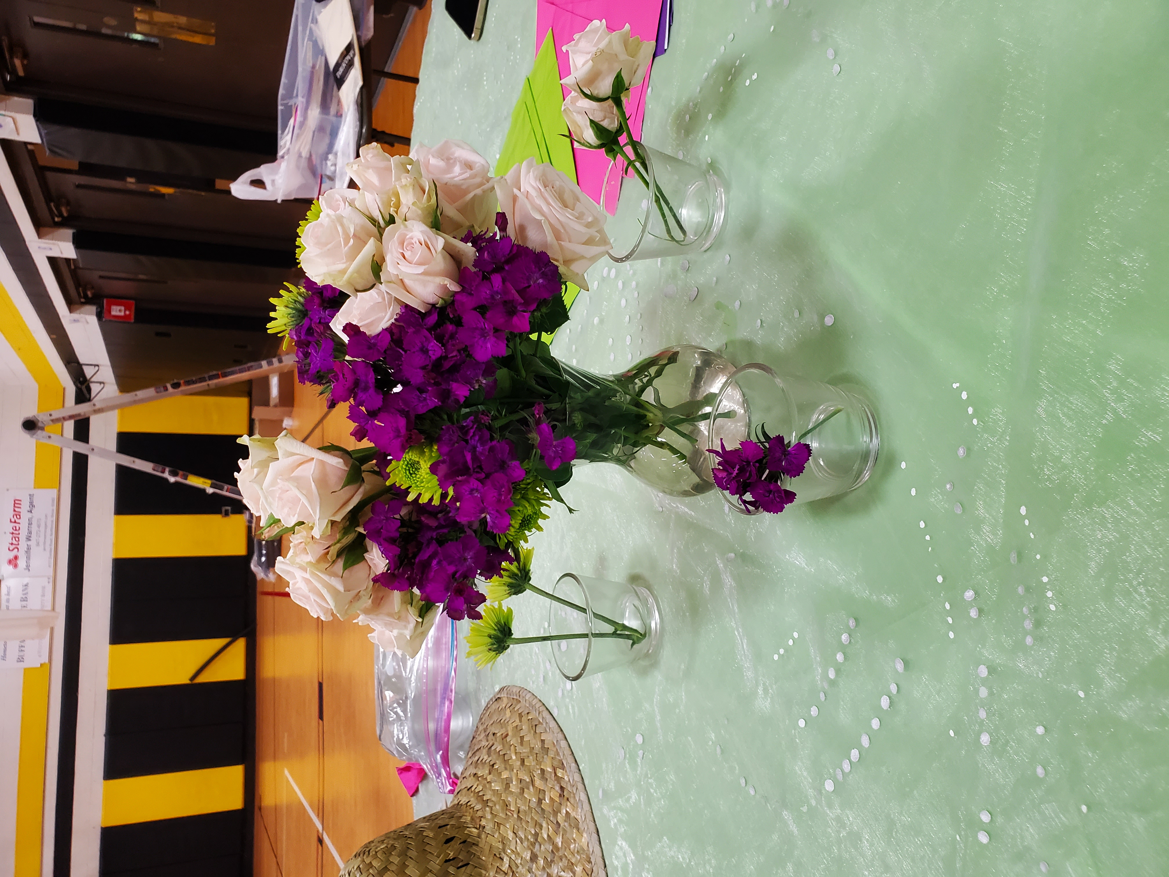 A bouqet in a clear glass vase with purple, white, and light green flowers