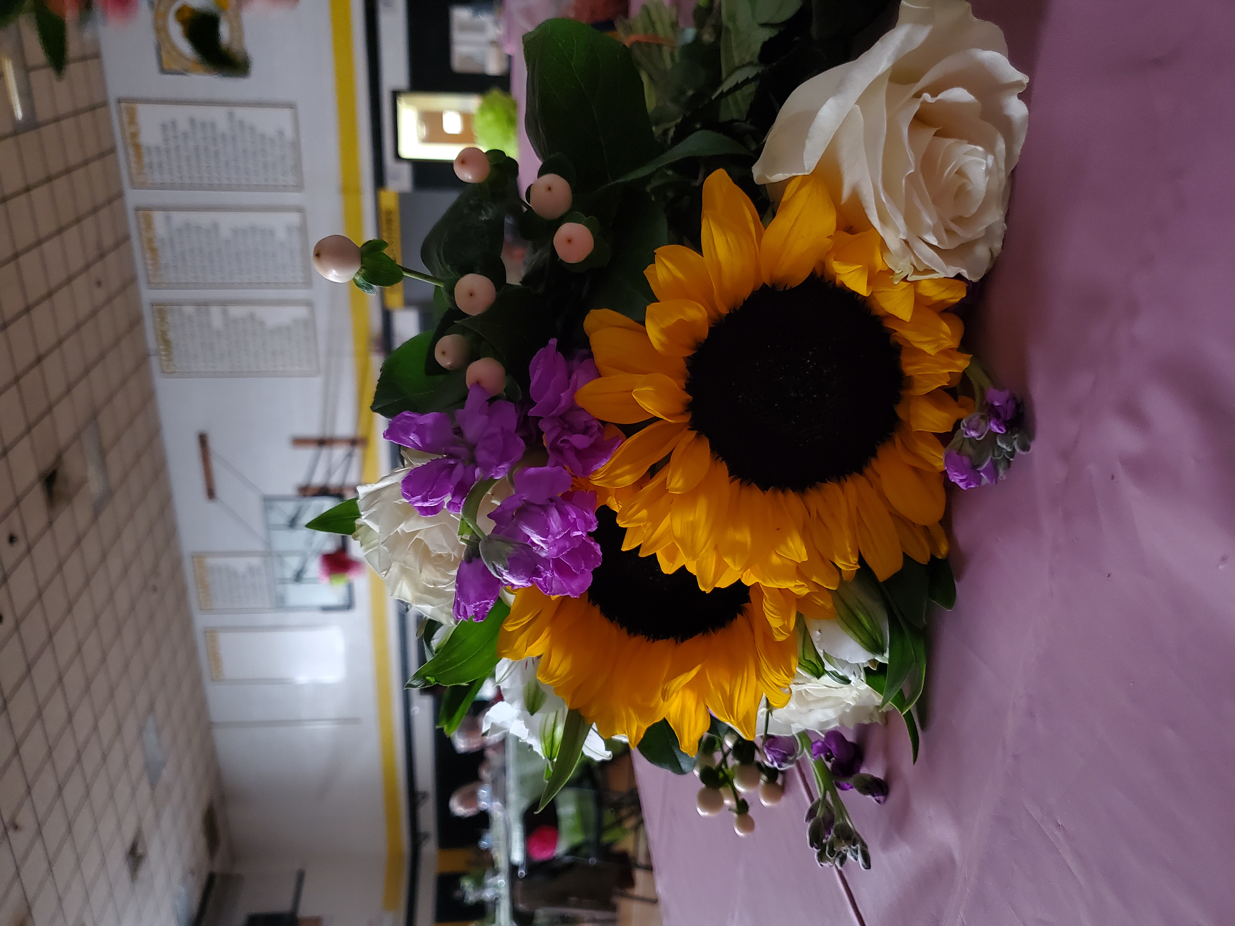 A close up photo of a bouquet with purple flowers and sunflowers