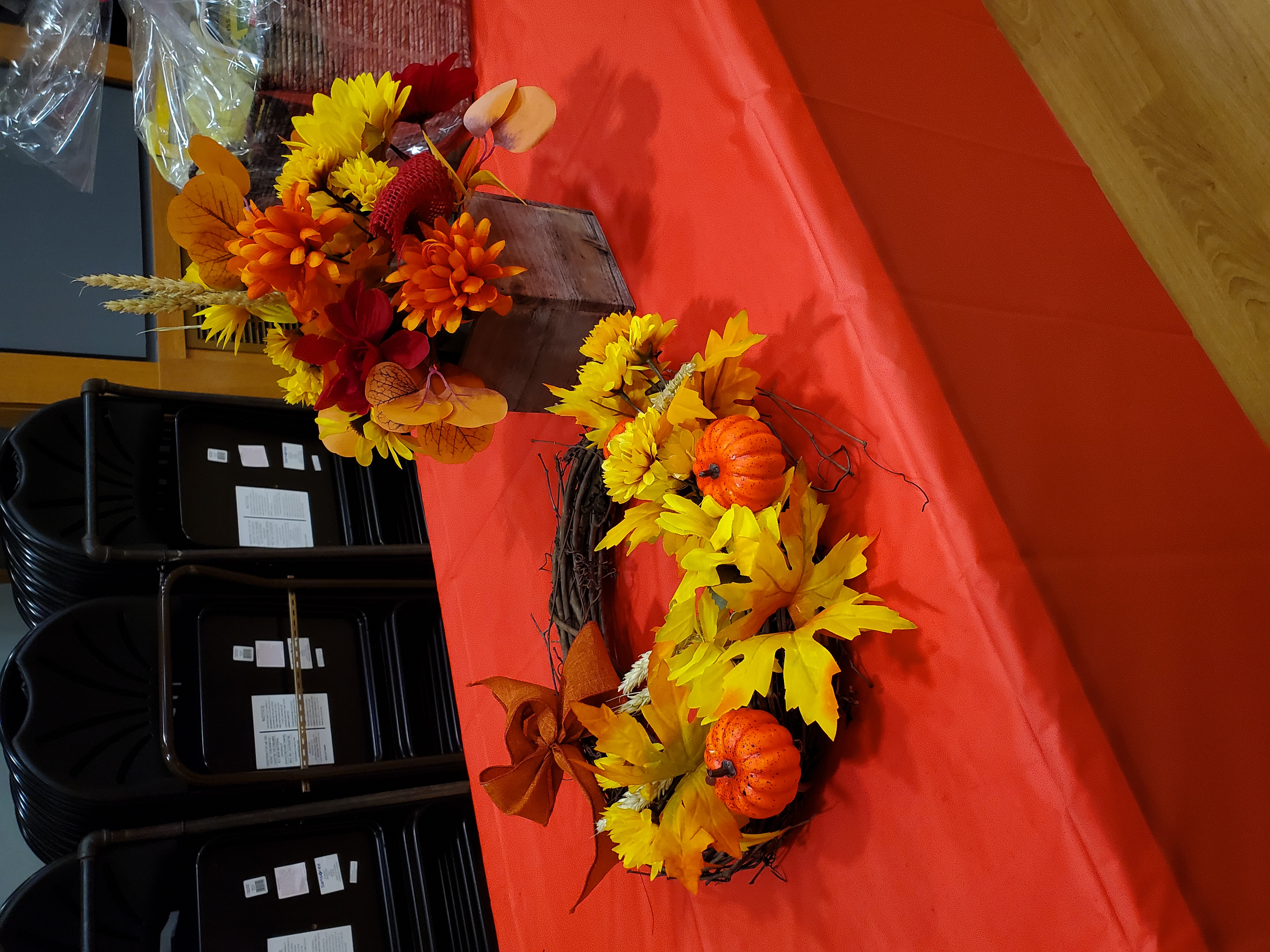 A photo of a fall themed bouquet and wreath with miniature pumpkins and orange and yellow flowers