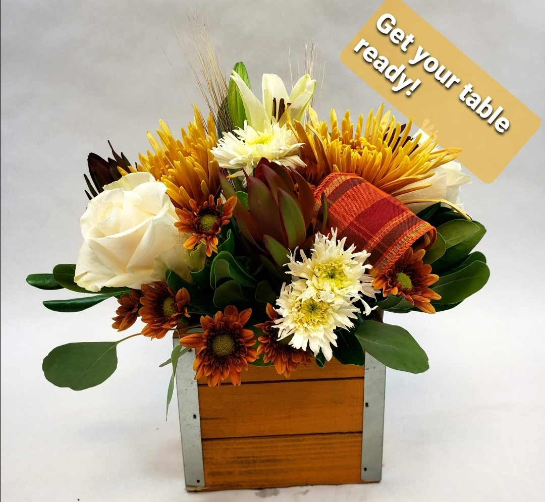 A fall themed bouquet with a piece of flannel fabric as well as orange and white flowers