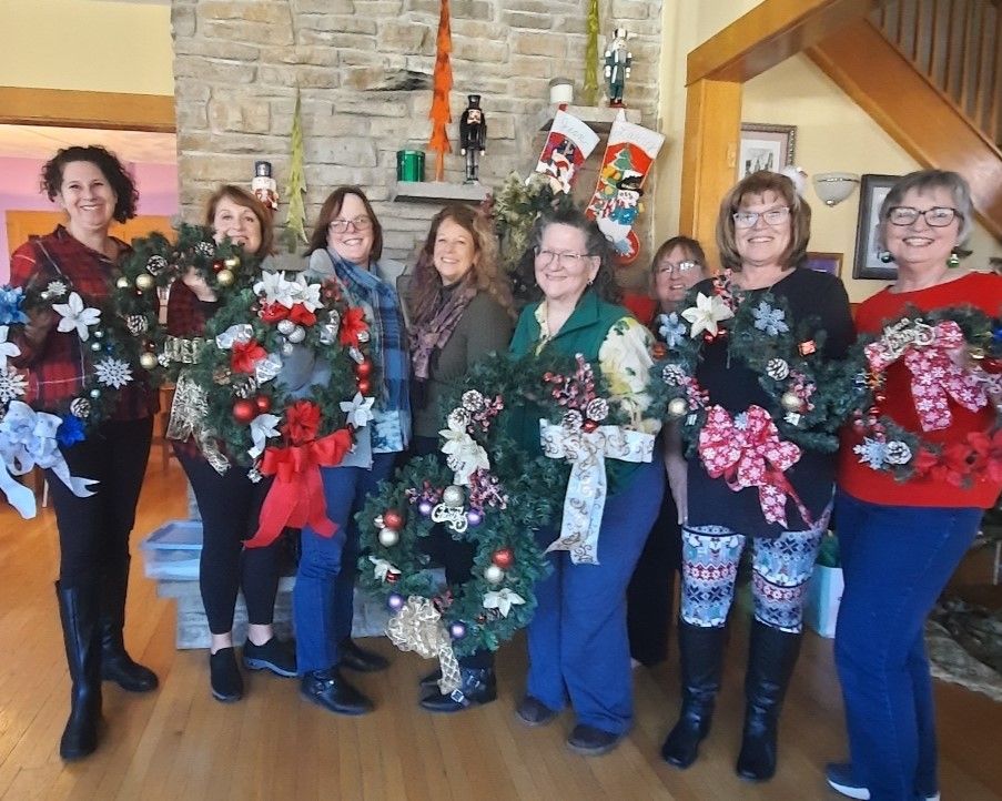 A group photo of ladies holding up their finished christmas wreaths