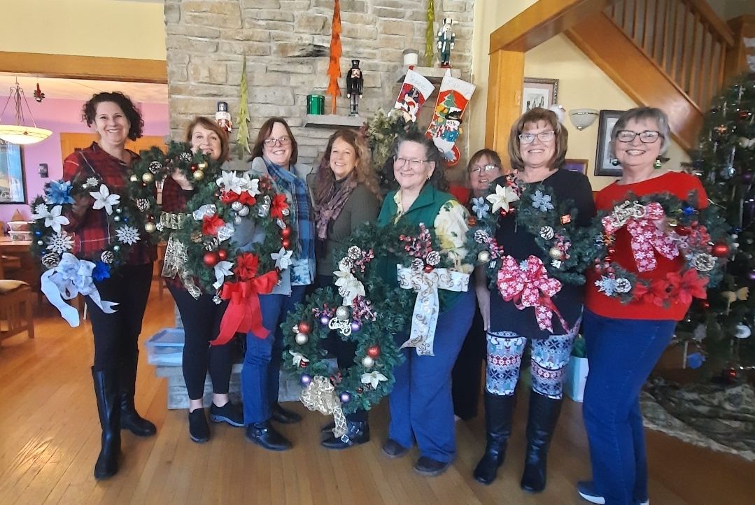 A group photo of ladies holding up their finished Christmas wreaths